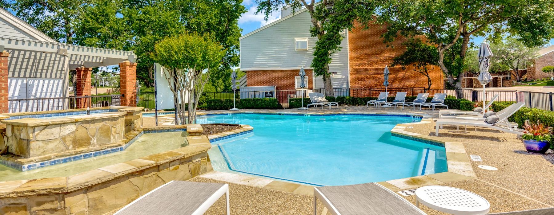 a swimming pool in a courtyard with lounge chairs